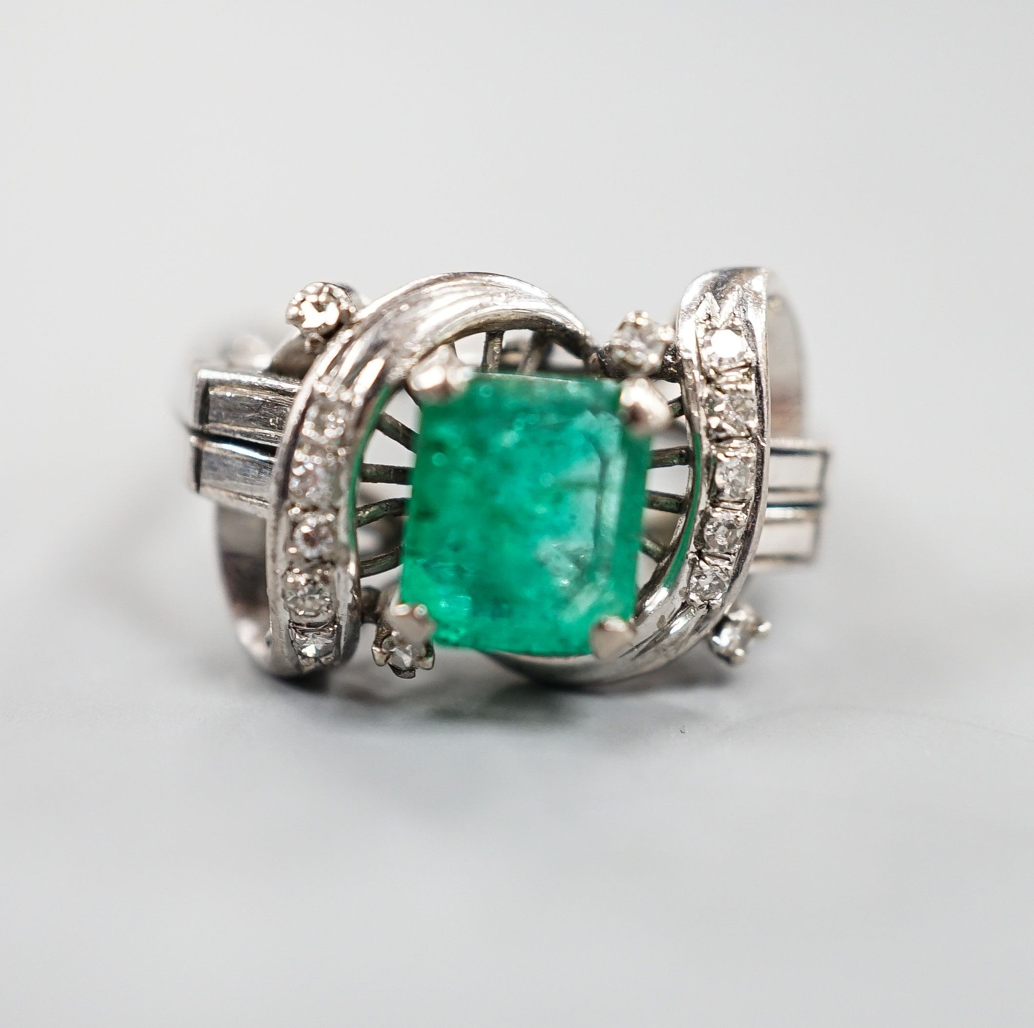 A modern 14k white metal and single stone emerald ring, with diamond chip set scroll setting, size K/L, gross weight 4.5 grams.